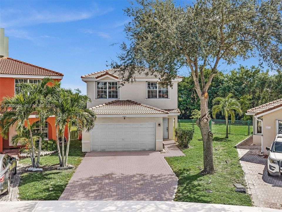 Stucco exterior featuring a dual-pitch tile roof, two-car garage, and a paved driveway