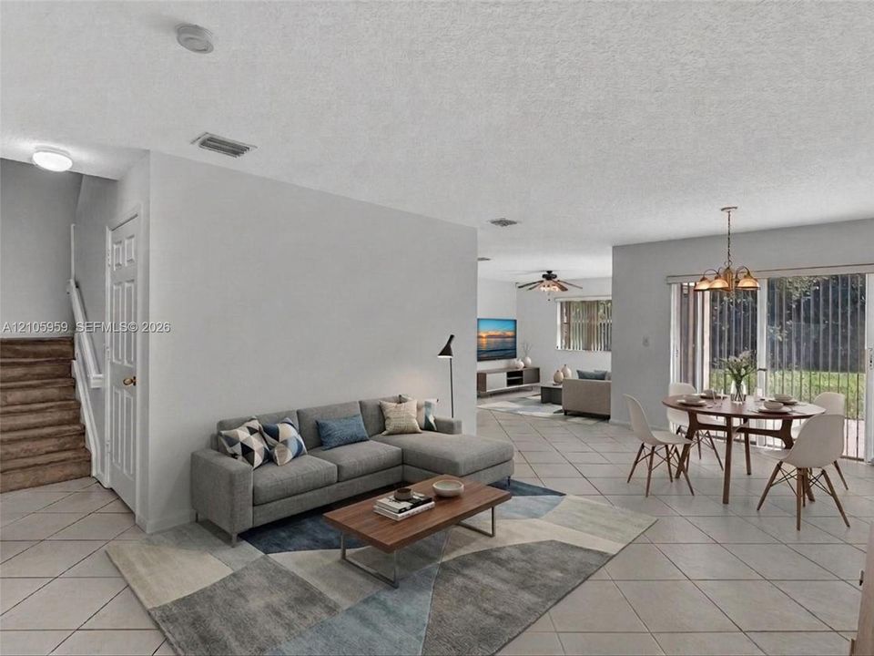 Open-concept interior featuring light-toned tile flooring, recessed lighting, a multi-light chandelier, and sliding glass doors