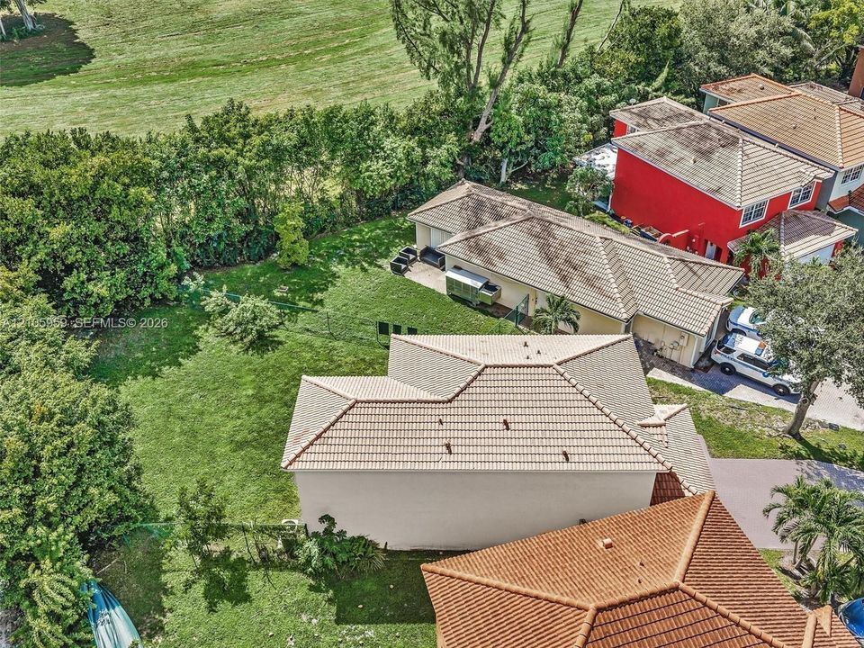 Expansive backyard featuring a manicured lawn, concrete patio, and tile roof structures