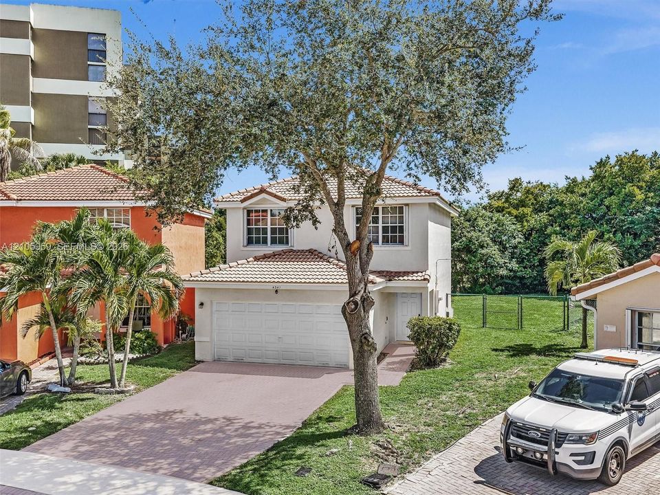 Two-story exterior featuring a tile roof, light-toned stucco facade, paved driveway, and attached two-car garage