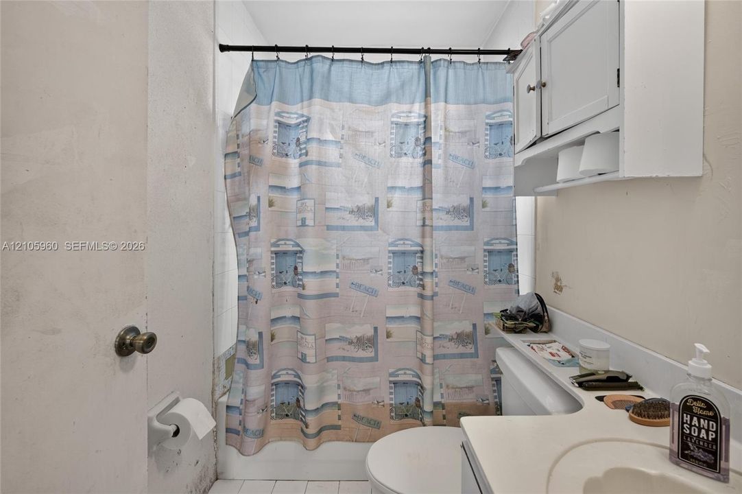 Bathroom featuring an integrated vanity countertop with a recessed basin, a wall-mounted medicine cabinet with shelving, and a combination tub-and-shower unit