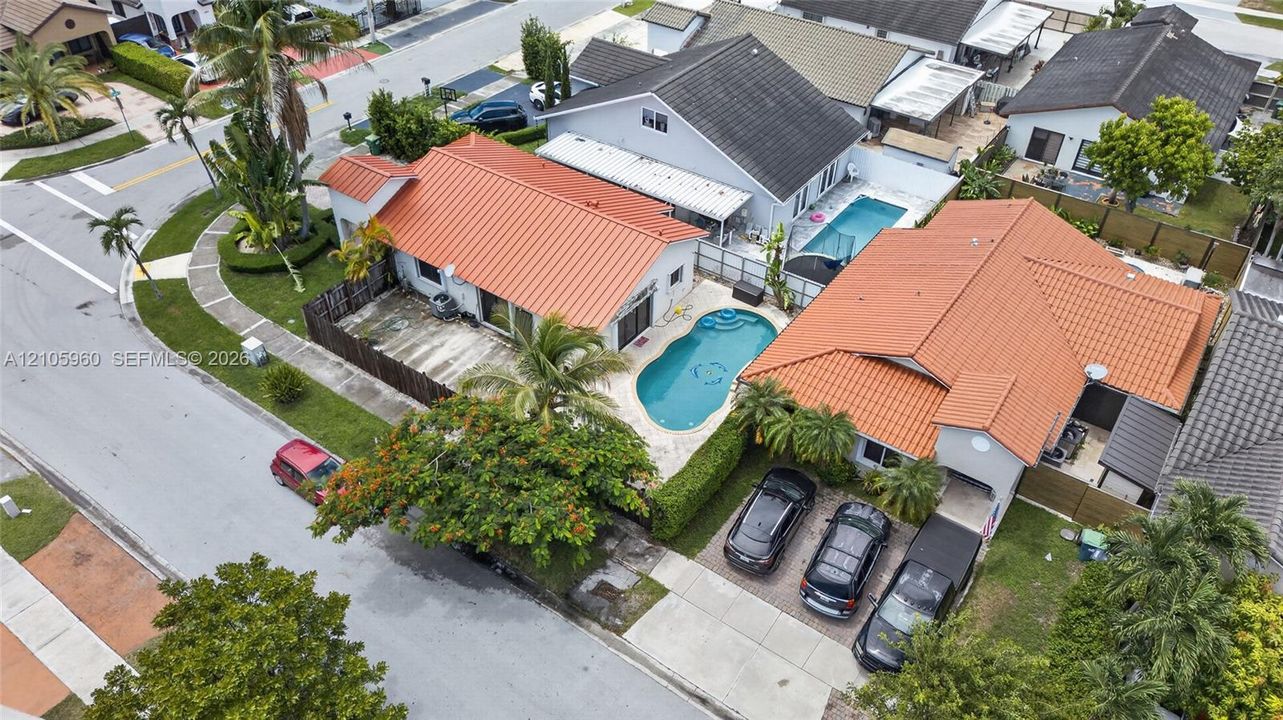 Single-story residence featuring a standing-seam metal roof, private in-ground pool, hardscaped patio, and a concrete driveway