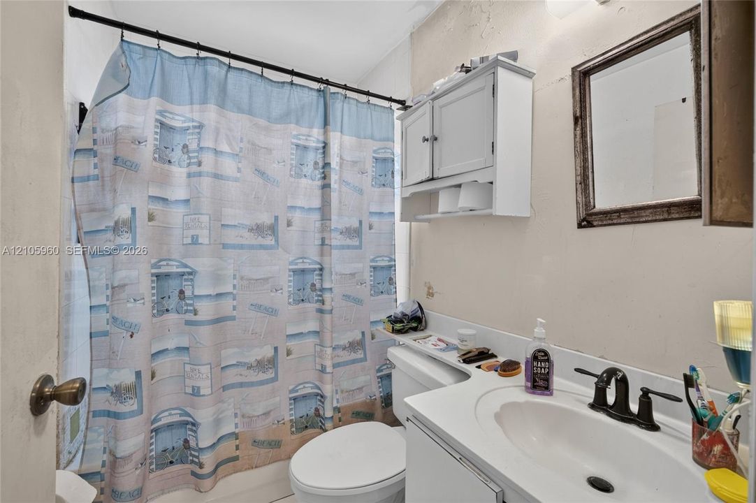 Bathroom featuring an integrated vanity with an oval sink, high-arc faucet, wall-mounted storage cabinet, and rectangular mirror