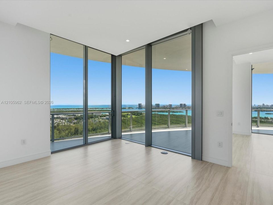 Floor-to-ceiling glass corner windows, wood-finish tile flooring, recessed ceiling lighting, and a wrap-around balcony with glass railings