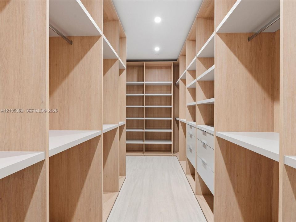 Custom closet featuring light-toned wood cabinetry, built-in shelving, integrated hanging rods, and soft-close drawer storage