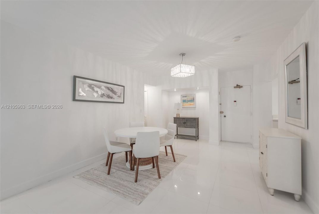 Polished white flooring, recessed accent lighting in a dedicated alcove, and a decorative drum-style chandelier