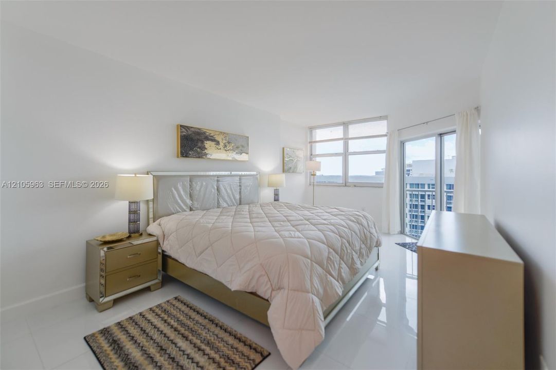 Spacious room featuring polished tile flooring, expansive floor-to-ceiling windows, and sliding glass door access to a balcony