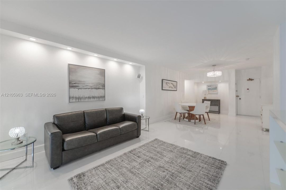 Bright living area featuring high-gloss flooring, recessed ceiling lighting, and a custom architectural soffit with integrated downlighting