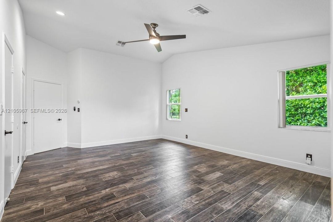 Vaulted ceilings, wood-finish flooring, recessed lighting, and a multi-blade ceiling fan
