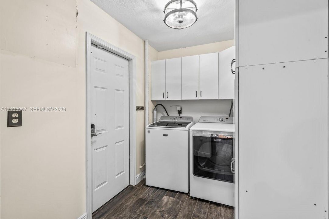 Laundry area featuring white built-in upper cabinetry, wood-finish flooring, and a semi-flush mount ceiling light fixture
