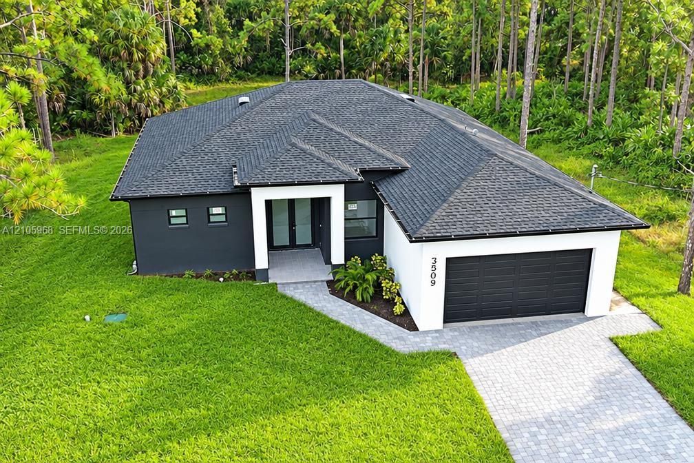 Contemporary exterior featuring high-contrast stucco finish, shingle roofing, integrated two-car garage, and paver driveway