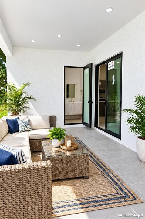 Covered patio featuring large-format ceramic tile flooring, recessed lighting, and black-framed sliding glass doors