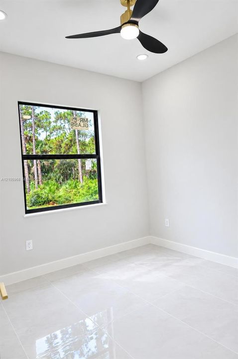 Interior space featuring large-format tile flooring, a modern three-blade ceiling fan with integrated light, recessed lighting, and a window with a black frame