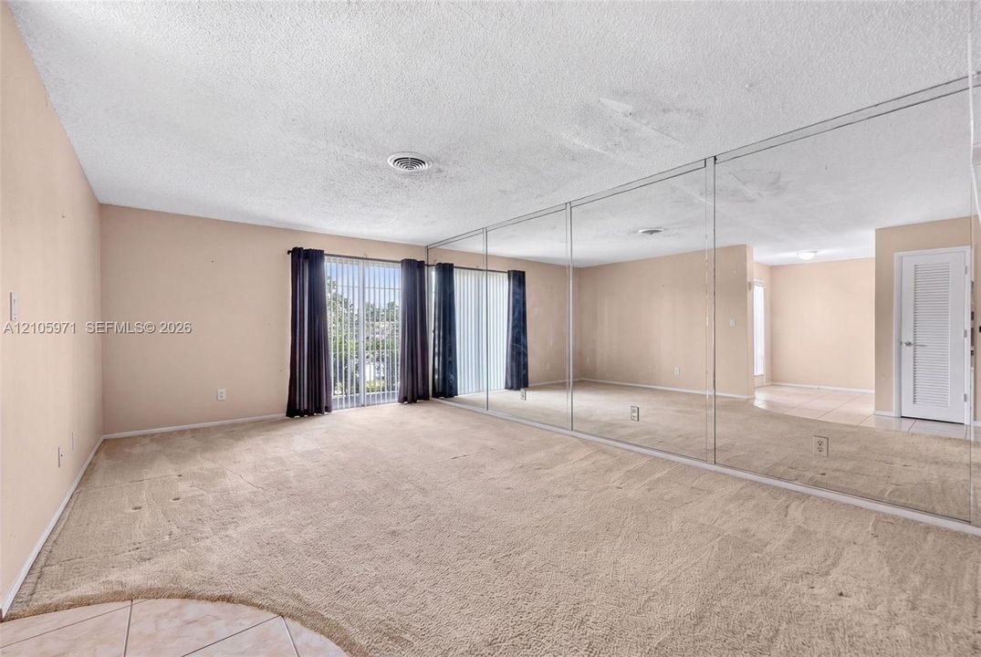 Floor-to-ceiling wall mirrors, sliding glass door, carpeted flooring, and a multi-panel interior door