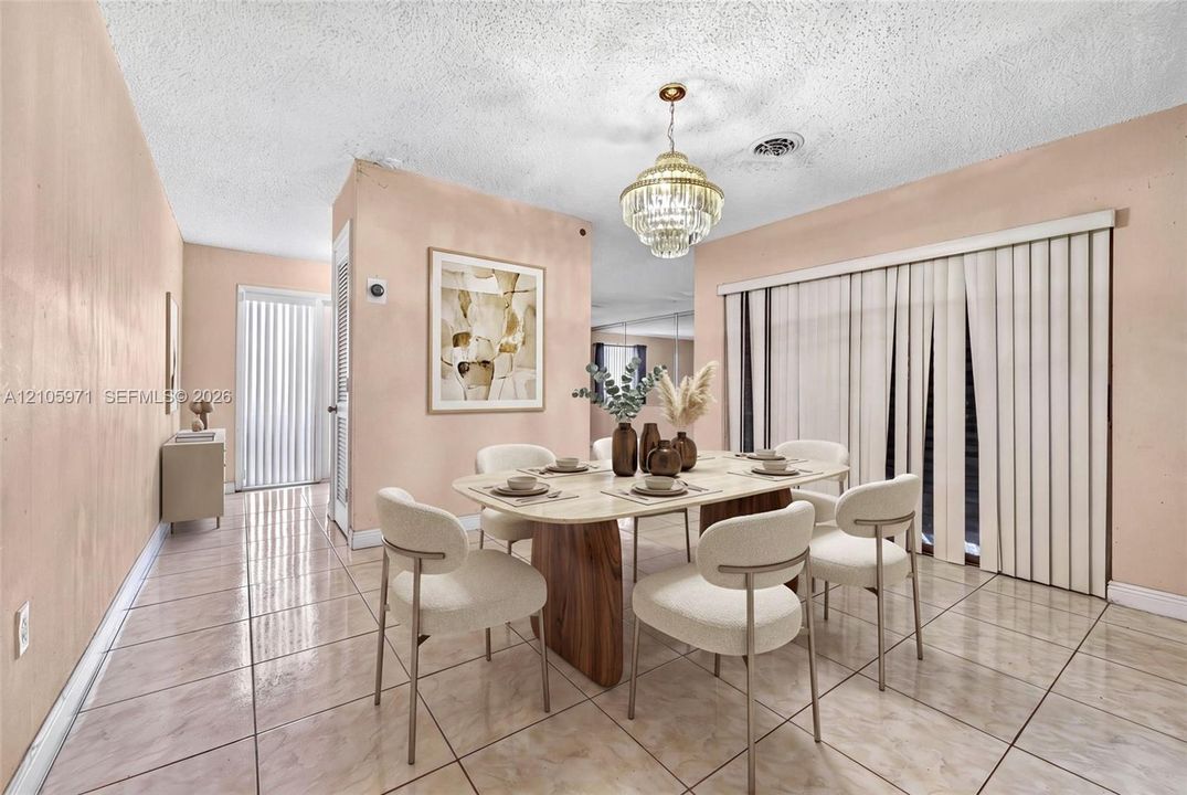 Dining area featuring polished tile flooring, a multi-tiered crystal chandelier, vertical blinds, and a built-in mirrored wall panel