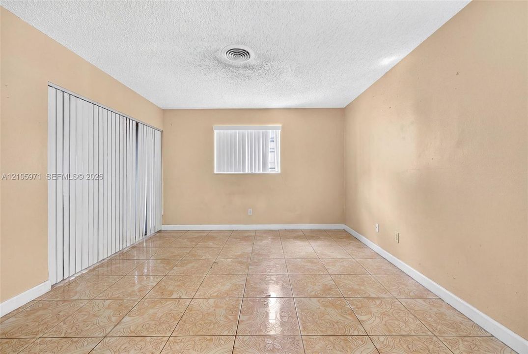Room featuring ceramic tile flooring, vertical window blinds, and a large sliding glass door