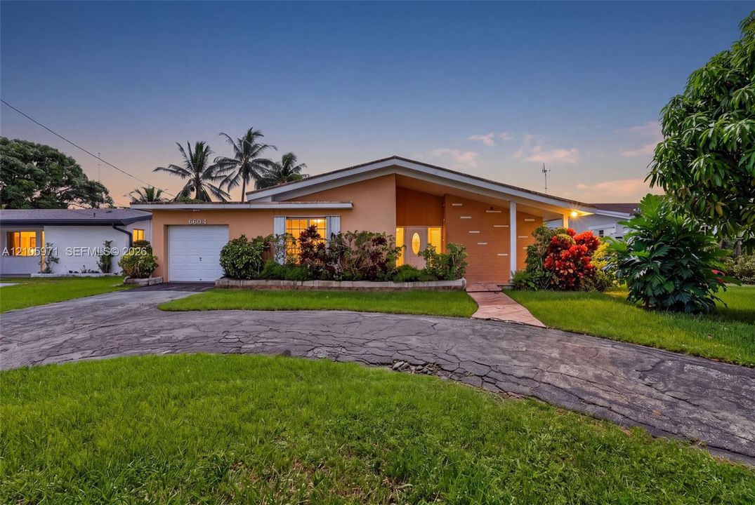 Mid-century modern architectural style featuring a low-pitch roofline, integrated single-car garage, stone masonry accents, and a winding driveway