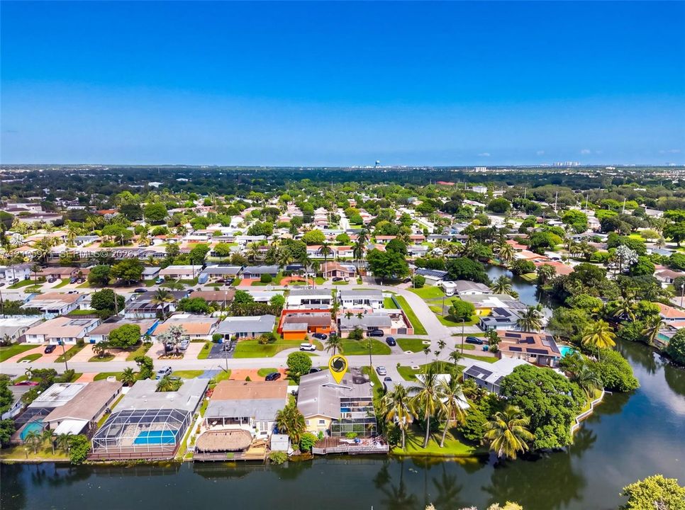 Aerial perspective of a waterfront property featuring a screened-in lanai, concrete seawall, mature palm trees, and direct canal access