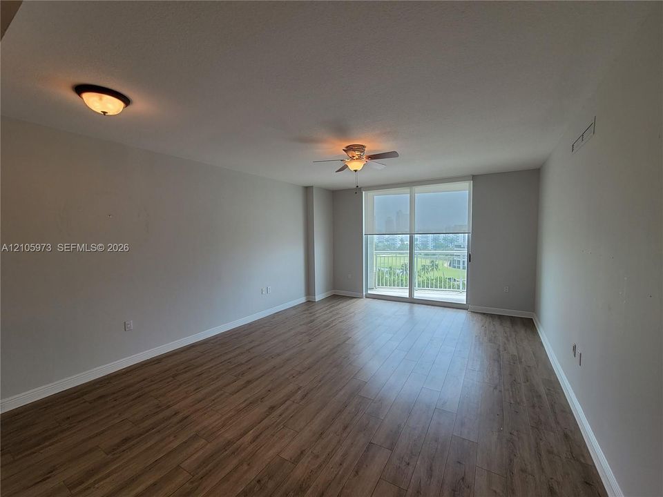 Open-concept room featuring wood-finish flooring, ceiling fan, flush-mount lighting, and large sliding glass door with access to a balcony