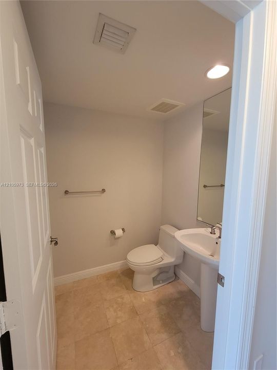 Powder room featuring a pedestal sink, polished stone flooring, recessed lighting, and a wall-mounted mirror