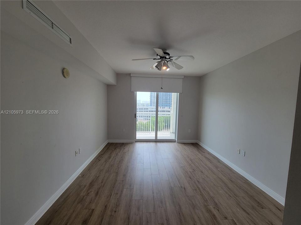 Living space featuring wood-finish flooring, a ceiling fan with integrated lighting, and sliding glass doors with access to an exterior balcony