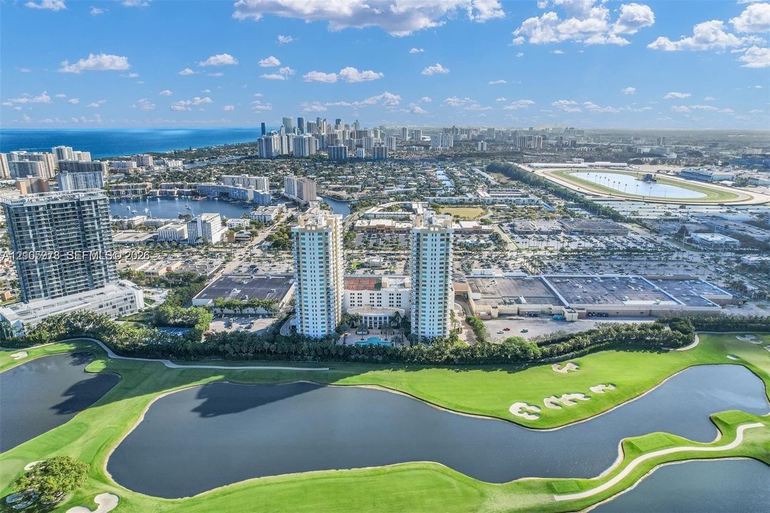 Aerial perspective featuring twin high-rise residential buildings situated on a golf course with expansive water features and mature landscaping
