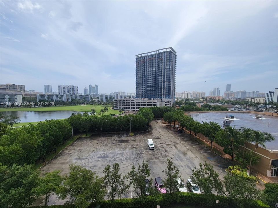 High-rise urban perspective featuring a panoramic cityscape, surrounding green space, and a large body of water