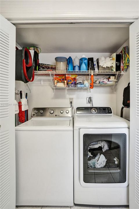 Laundry area featuring louvered bi-fold closet doors, white tile flooring, and integrated wire shelving