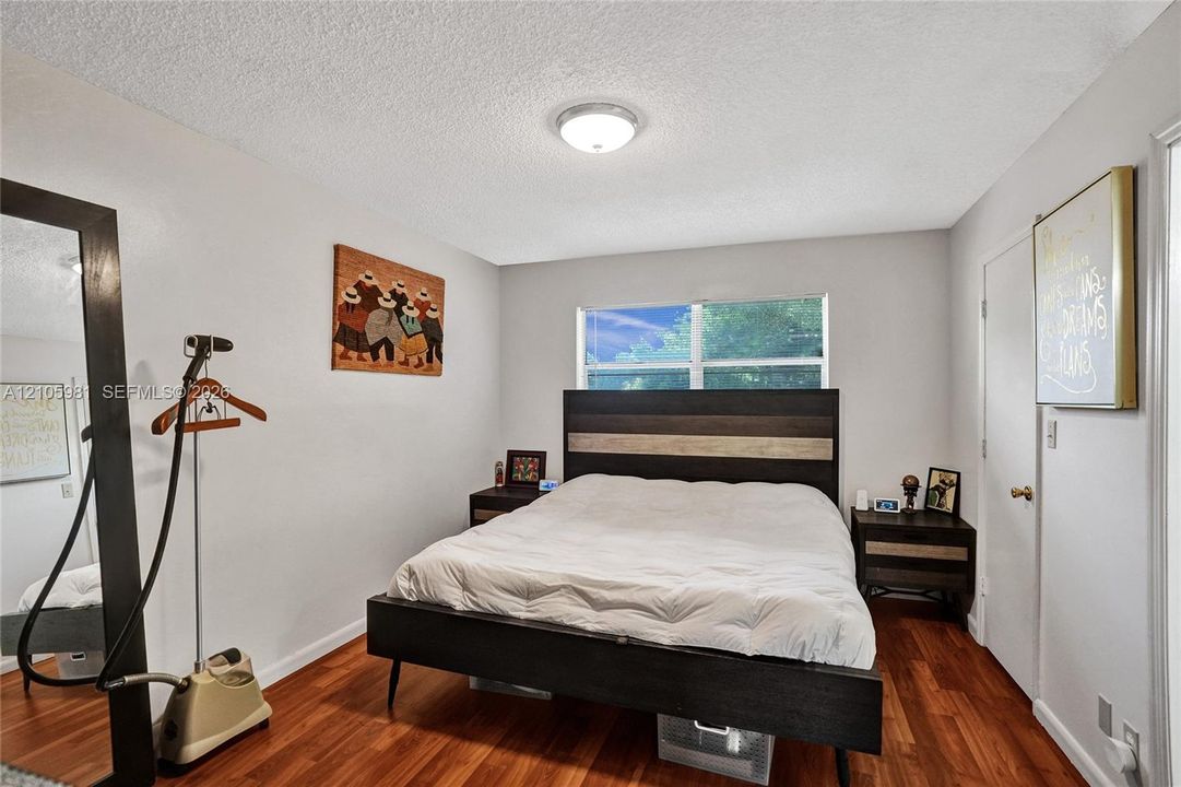 Room interior featuring wood-finish flooring, a double-hung window, and a flush-mount ceiling light fixture