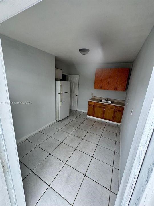 Kitchen featuring ceramic tile flooring, wood cabinetry, a stainless steel sink, and a flush-mount ceiling light fixture