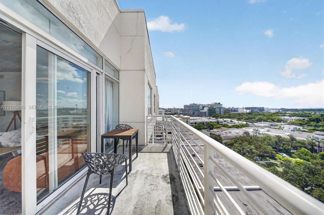 Private balcony featuring concrete flooring, a horizontal metal railing, and floor-to-ceiling sliding glass doors