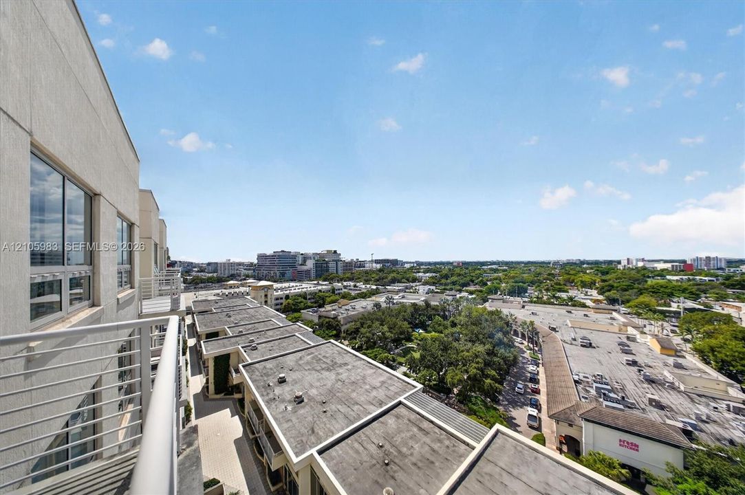 Elevated balcony featuring horizontal metal railings, large-format glass windows, and expansive urban scenery
