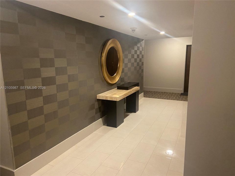 Geometric patterned wall covering, recessed ceiling lighting, and polished tile flooring