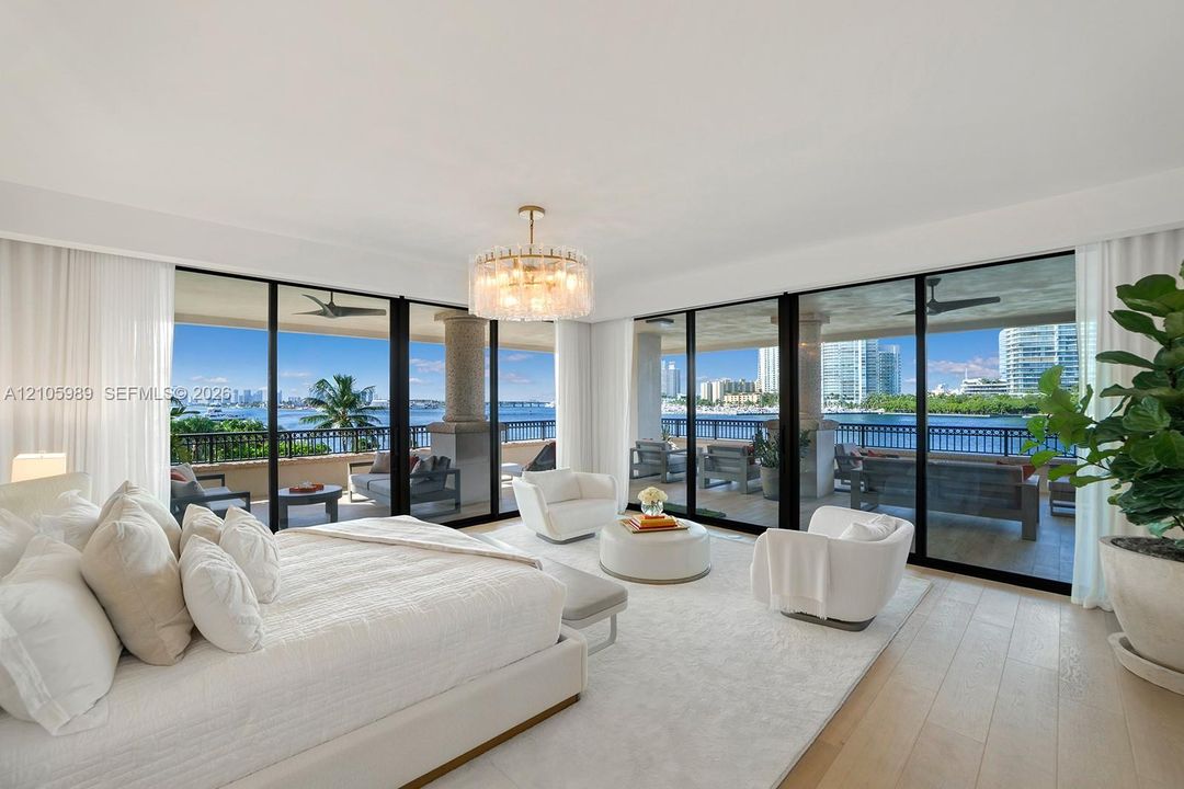 Floor-to-ceiling glass sliding doors, wood-finish flooring, crystal drum pendant chandelier, and expansive covered balcony with railings