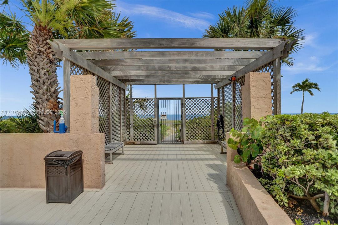 Wood-frame pergola with lattice side panels, solid surface decking, integrated benches, and gated access