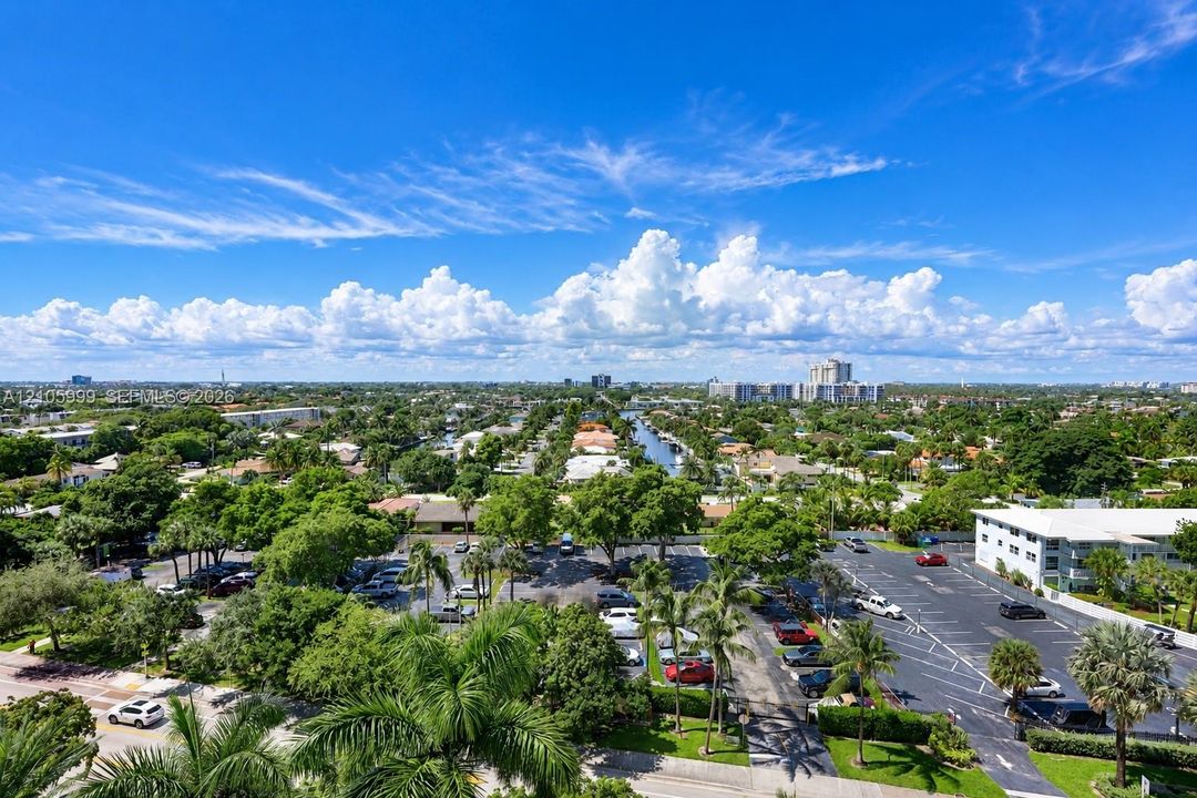 Aerial perspective featuring paved parking areas, mature palm trees, established landscaping, and a central waterway