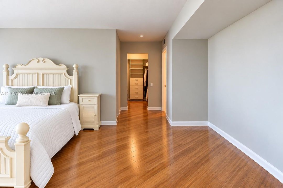 Spacious room featuring wood-finish flooring, recessed lighting, and a walk-in closet with built-in shelving and drawers