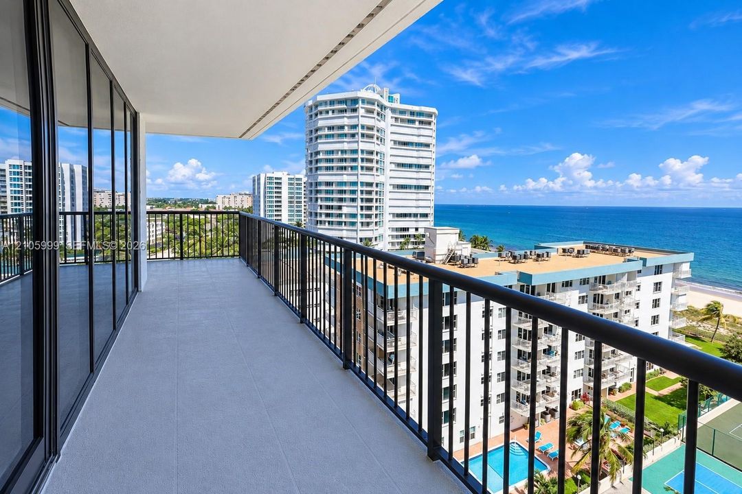 Private balcony featuring tile flooring, metal railings, floor-to-ceiling glass sliding doors, and water scenery