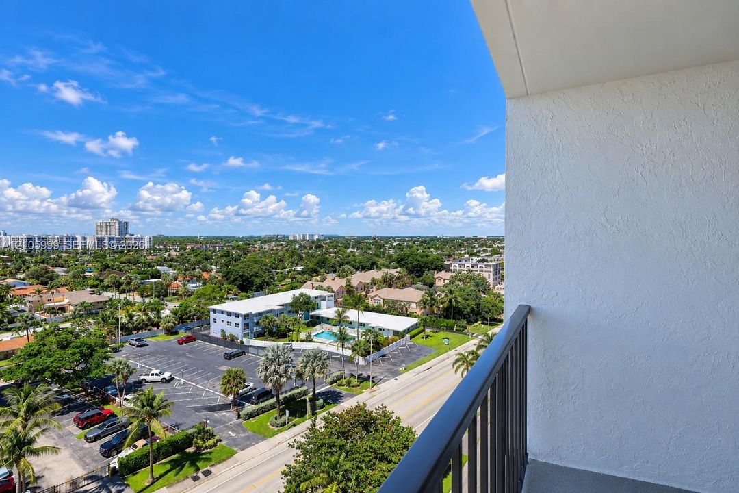 Private balcony featuring a textured stucco wall and metal railing with expansive city and landscape scenery