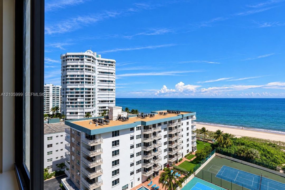 Elevated coastal perspective featuring oceanfront scenery, multiple high-rise structures, a private tennis court, and sandy coastline