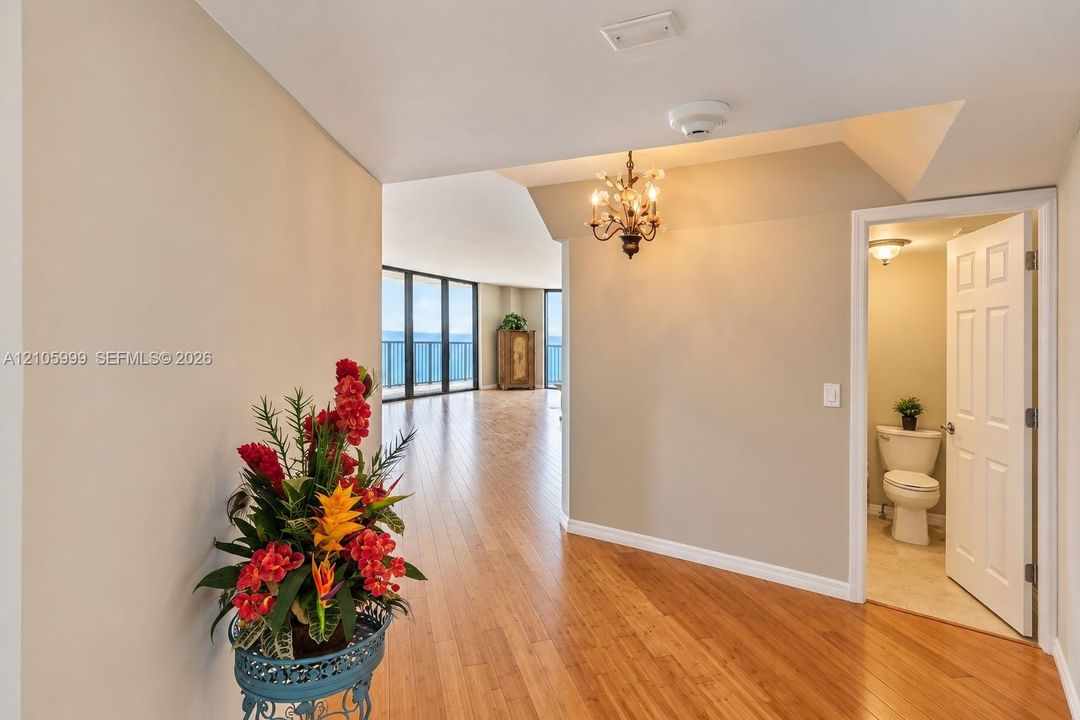 Interior entry featuring wood-finish flooring, a multi-arm metallic chandelier, and a powder room with tile flooring and a porcelain toilet