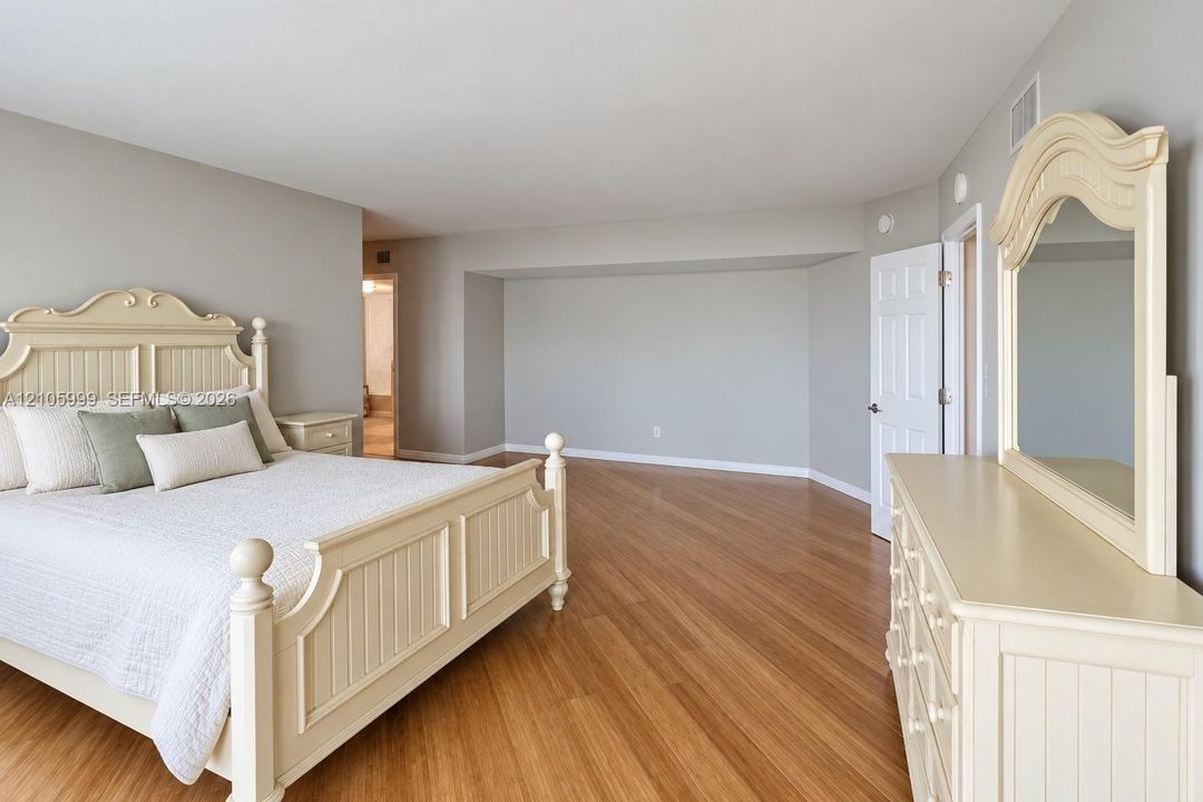 Spacious room featuring wood-finish flooring, neutral wall paint, and a multi-panel door