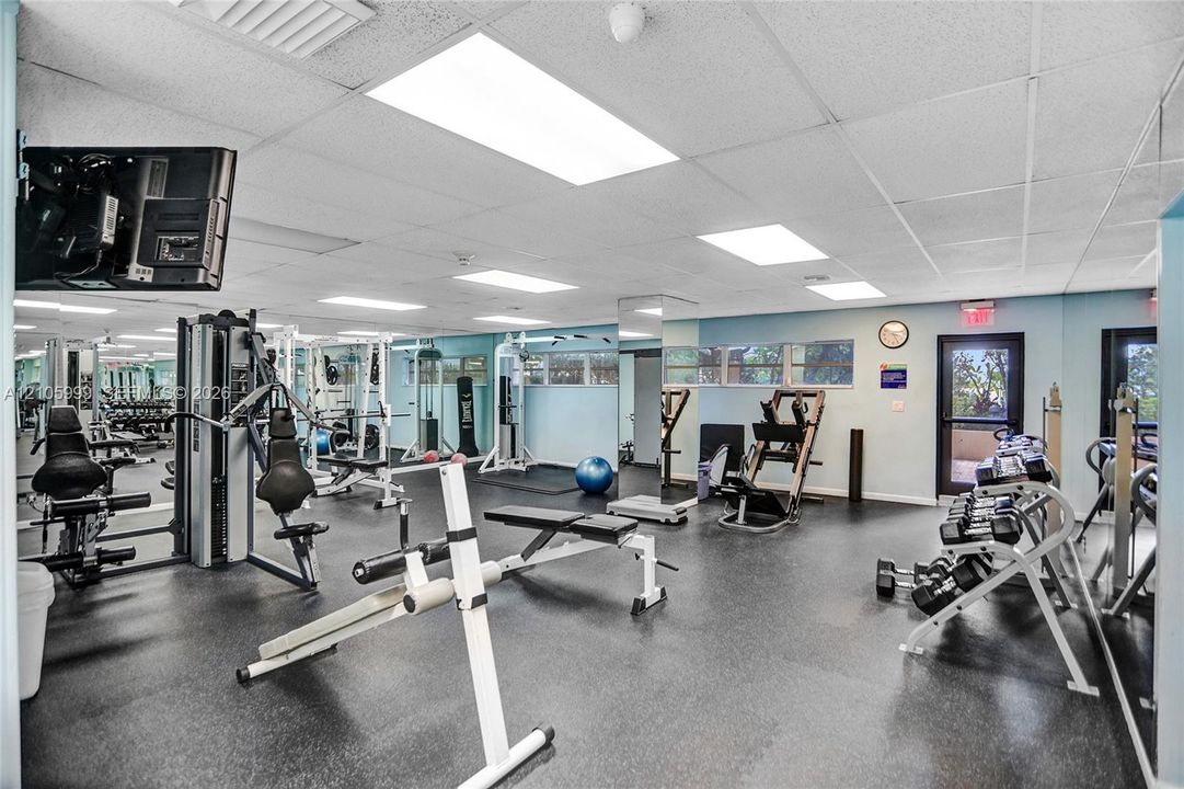 Fitness facility featuring rubberized flooring, recessed panel lighting, floor-to-ceiling mirror wall panels, and multiple exterior-facing windows