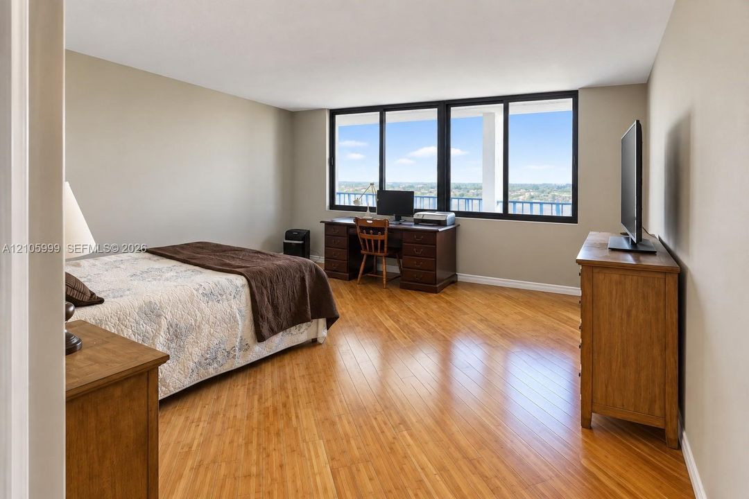 Wood-finish flooring, neutral wall tones, and expansive windows featuring black frames and outdoor scenery
