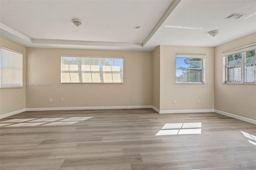Spacious interior featuring wood-finish flooring, tray ceilings, and multiple windows