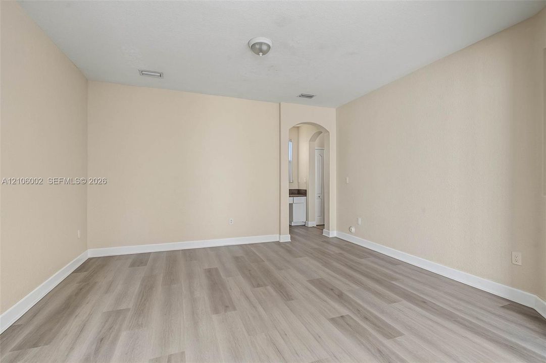 Interior space featuring wood-finish flooring, neutral wall tones, and a structural arched entryway