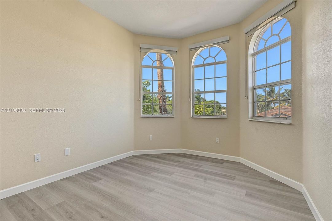 Bay window featuring three arched, multi-pane windows and wood-finish flooring