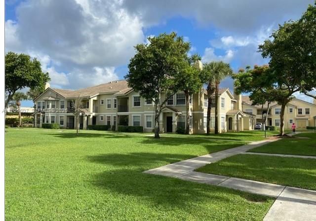 Multi-story building featuring stucco exterior, shingle roofing, private balconies, covered entryways, and concrete walkways