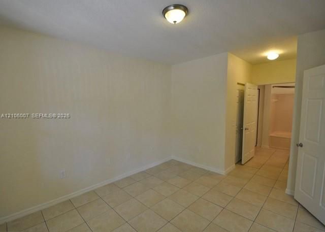 Interior room featuring neutral-toned tile flooring, light-colored walls, flush-mount ceiling light fixtures, and multi-panel interior doors