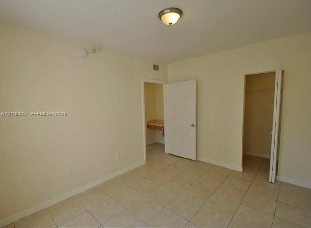Interior space featuring light-colored tile flooring, neutral wall tones, a six-panel door, built-in shelving, and a dual-fold closet door